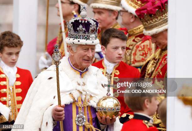 Britain's King Charles III wearing the Imperial state Crown carrying the Sovereign's Orb and Sceptre leaves Westminster Abbey after the Coronation...