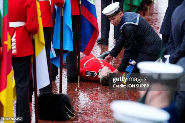 Assistance is provided to a flag bearer after collapsing during a procession following the Coronation Ceremony for King Charles III and Queen Camilla...