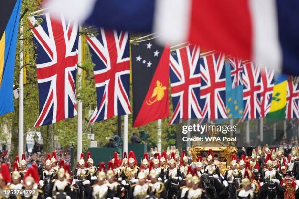 King Charles III and Queen Camilla are carried in the Diamond Jubilee State Coach as the King's Procession passes along The Mall to their coronation...