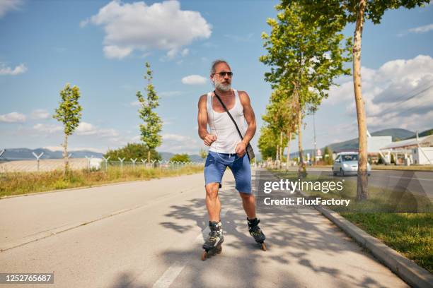 hogere mens op rolschaatsen die van een rit in openlucht genieten - skaten stockfoto's en -beelden