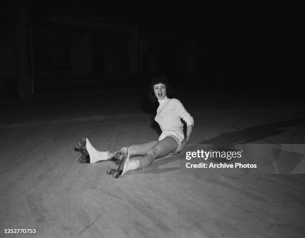 Young woman falls over while roller skating and hurts her rear, USA, circa 1950.