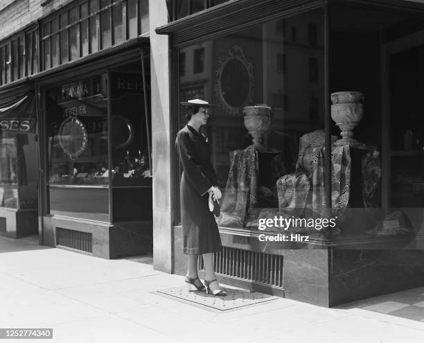 Model Carol Carter looks at two stone urns in the window of a shop on Madison Avenue and 63rd Street in New York City, June 1938.