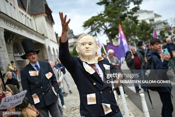 Protester wearing a mask of French businessman Bernard Arnault gestures during a demonstration called by unions trade parodying the wealthy class, in...