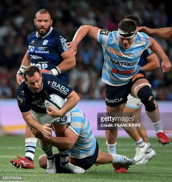 Bayonne's French fly half Camille Lopez is tackled by Racing 92's French hooker Janick Tarrit during the French Top14 rugby union match between...