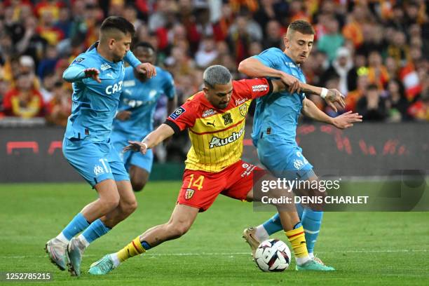 Lens' Argentine defender Facundo Medina fights for the ball with Marseille's Turkish forward Cengiz Under and Marseille's French midfielder Valentin...