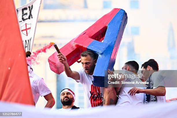 Domenico Criscito of Genoa lights a smoke-bomb as players of Genoa reach the centre of town on a double-decker bus to celebrate after earning...