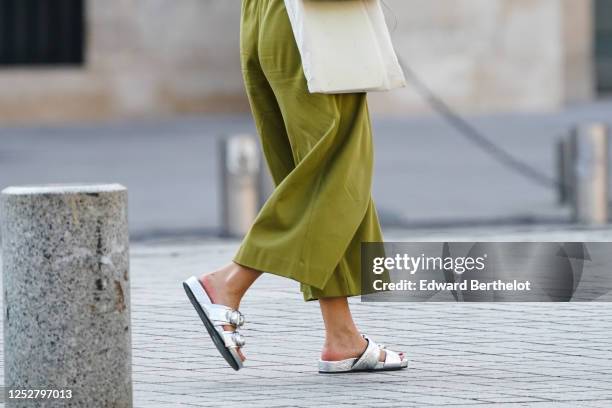 Passerby wears green flared cropped pants, silver shoes, on June 25, 2020 in Paris, France.