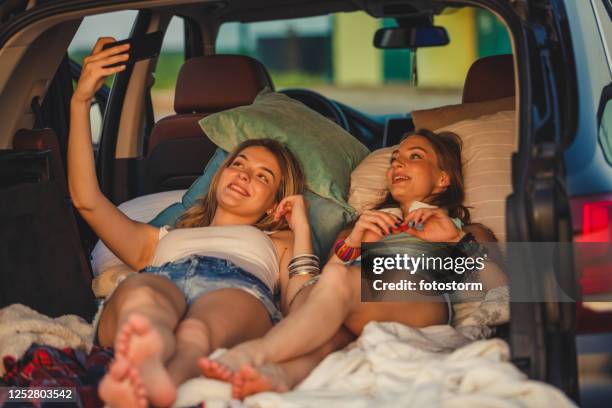 freedom and relaxation in the car trunk for a couple of lively women - sleeping in car stock pictures, royalty-free photos & images