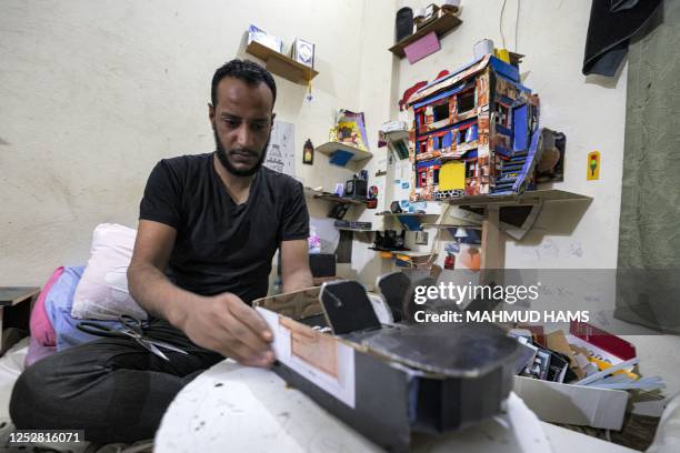 In this picture taken on April 1 Mohamed Abu Taima, a 34-year-old Palestinian, assembles cardboard figures he fabricates with his wife to be used as...