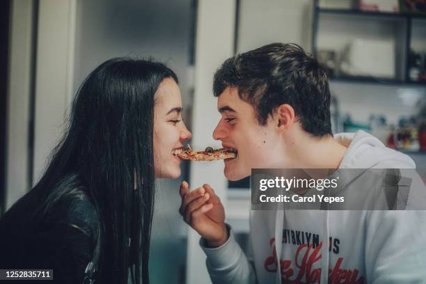 young teenager copule sharing slice  of pizza at home - boyfriend foto e immagini stock