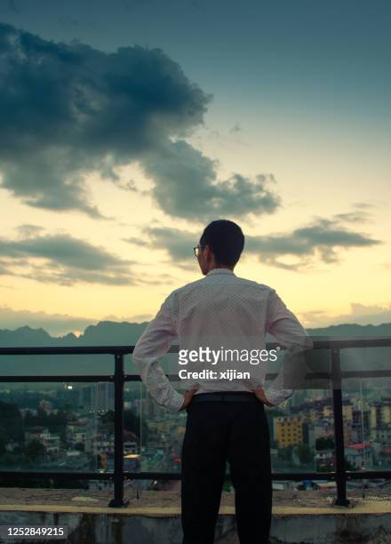 geschäftsmann steht auf einem gebäude, das sonnenuntergang aussieht - lateinamerika stock-fotos und bilder