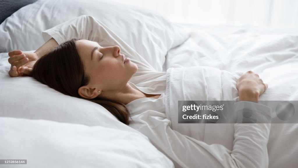 Donna calma che dorme tranquillamente in un letto accogliente