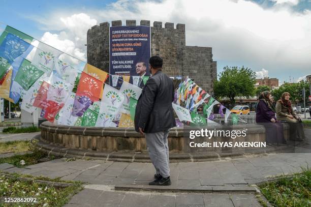 Man walks past election campain flags of People's Democratic Party and a banner with a portrait of Turkish President Recep Tayyip Erdogan hanging on...