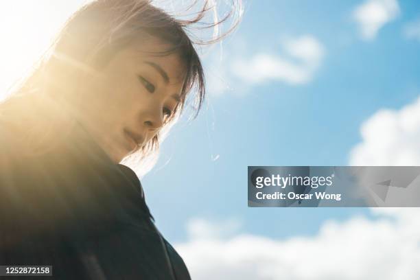 young woman having hope for the future - young woman standing against clear sky ストックフォトと画像