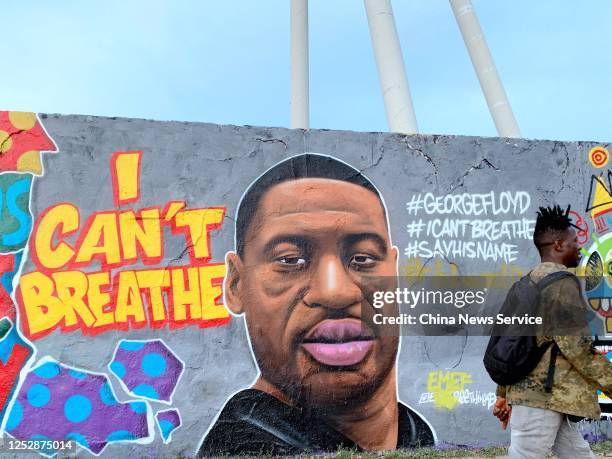 Man walks past a graffiti on a wall depicting a portrait of George Floyd, an unarmed black man who died in Minneapolis after a white policeman knelt...