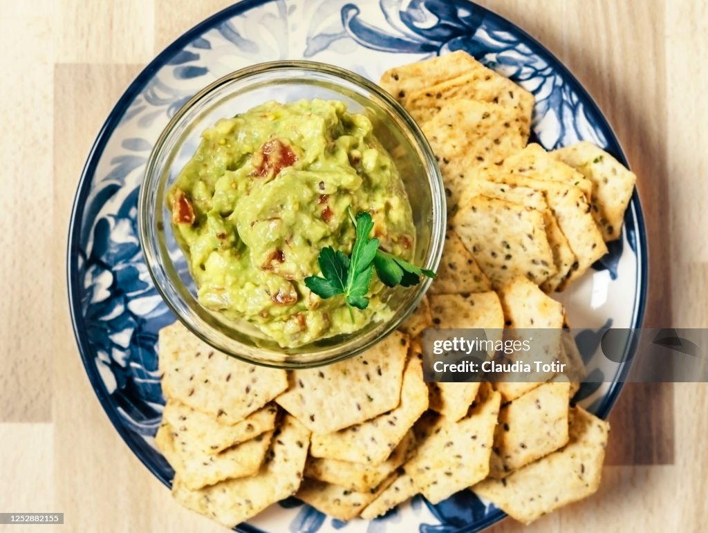 Plate of chips and guacamole on wooden background