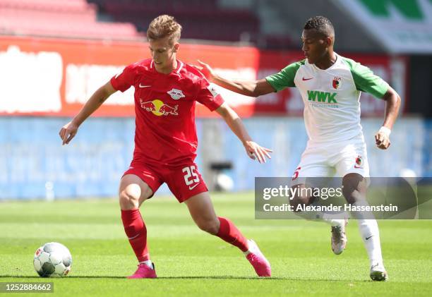 Dani Olmo of Red Bull Leipzig is challenged by Carlos Gruezo of FC Augsburg during the Bundesliga match between FC Augsburg and RB Leipzig at...