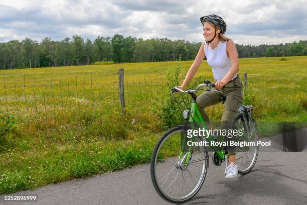 Princess Elisabeth of Belgium smiles while riding a bike during a visit with King Philippe of Belgium, Queen Mathilde of Belgium, Prince Gabriel of...
