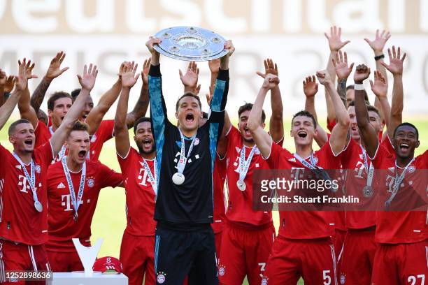 Team captain Manuel Neuer of FC Bayern Muenchen lifts the trophy to celebrate the championship following the Bundesliga match between VfL Wolfsburg...