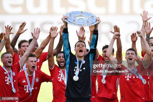 Team captain Manuel Neuer of FC Bayern Muenchen lifts the trophy to celebrate the championship following the Bundesliga match between VfL Wolfsburg...