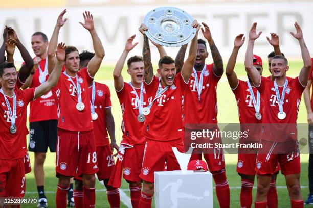 Lucas Hernandez of FC Bayern Muenchen lifts the trophy to celebrate the championship following the Bundesliga match between VfL Wolfsburg and FC...