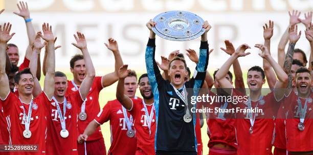 Team captain Manuel Neuer of FC Bayern Muenchen lifts the trophy to celebrate the championship following the Bundesliga match between VfL Wolfsburg...