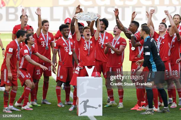 Joshua Kimmich of FC Bayern Muenchen lifts the trophy to celebrate the championship following the Bundesliga match between VfL Wolfsburg and FC...