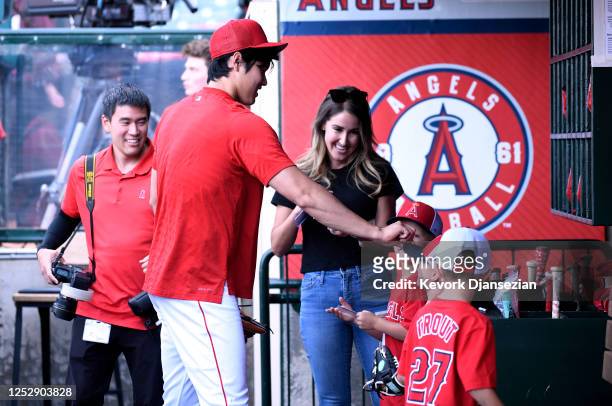 Shohei Ohtani of the Los Angeles Angels gives his autograph to kids in the dugout before the game against the Texas Rangers at Angel Stadium of...