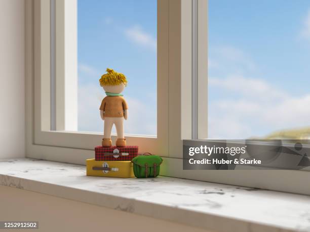 doll on stacked suitcases looks dreamily out of the window - looking through a doll house photos et images de collection