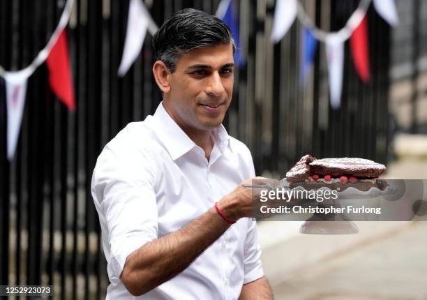 Prime Minister Rishi Sunak serves cake during a lunch in Downing Street to celebrate the coronation of King Charles III and Queen Camilla on May 07,...