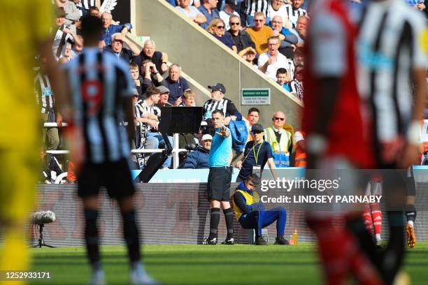 English referee Chris Kavanagh consilts the pitch-side monitor after the VAR advised him to check for a penalty for handball during the English...