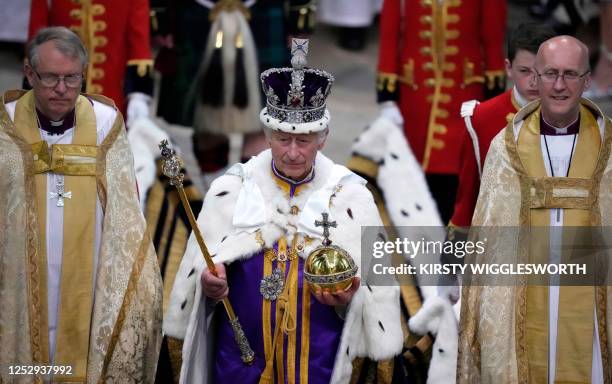 Britain's King Charles III, wearing the Imperial state Crown and carrying the Sovereign's Orb and Sceptre leaves after the Coronation Ceremony at...