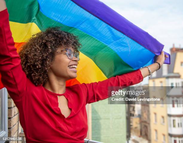 young lady waving a gay pride flag in support of gay pride - orgoglio foto e immagini stock