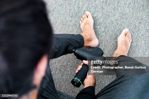 a man using massage gun / machine - percussion instrument stock pictures, royalty-free photos & images