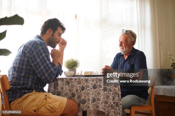 family playing chess together weekend activities - senior playing chess stock pictures, royalty-free photos & images