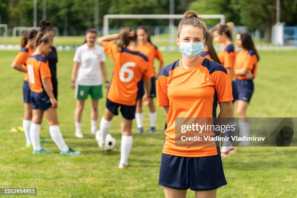 covid-19. retrato de un joven jugador de fútbol que usa máscara facial debido a la pandemia de coronavirus. - football face mask fotografías e imágenes de stock