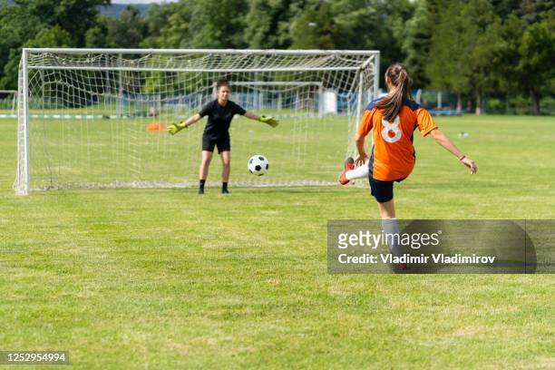 female soccer player practices shots on goal on a turf field - rematar à baliza imagens e fotografias de stock