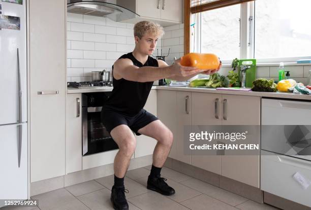 man doing indoor exercise workout at home during lock down by using milk bottle - auckland covid stock pictures, royalty-free photos & images