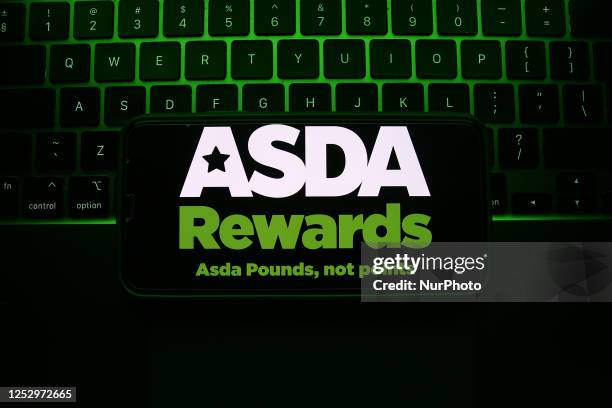 Laptop keyboard and ASDA Rewards logo displayed on a phone screen are seen in this illustration photo taken in Krakow, Poland on May 7, 2023.