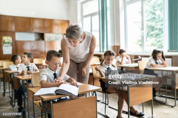 female teacher explains math solution to a schoolboy - private school uniform stock pictures, royalty-free photos & images