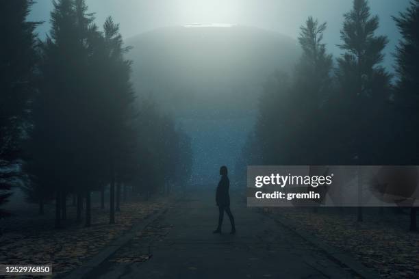 woman standing in country road against ufo - alien arrival stock pictures, royalty-free photos & images