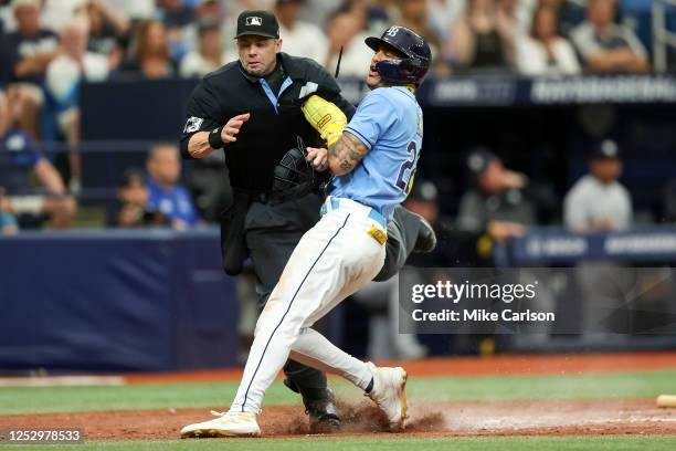 Jose Siri of the Tampa Bay Rays collides with umpire Will Little after scoring against the New York Yankees during the sixth inning at Tropicana...