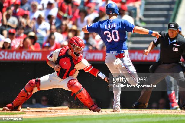 Texas Rangers first baseman Nate Lowe touches home plate before the tag from Los Angeles Angels catcher Matt Thaiss to score a run during the MLB...