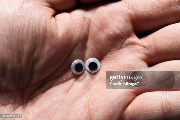 googly eyes in the palm of hand - wackelaugen stock-fotos und bilder