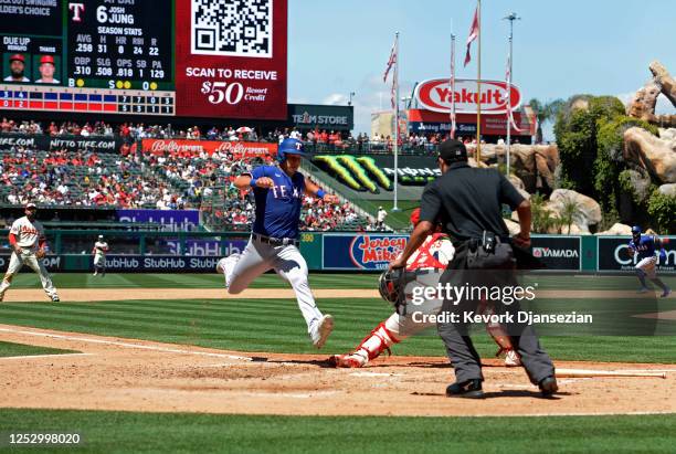 Catcher Matt Thaiss of the Los Angeles Angels losses the ball trying to tag out Nathaniel Lowe of the Texas Rangers during the fourth inning at Angel...