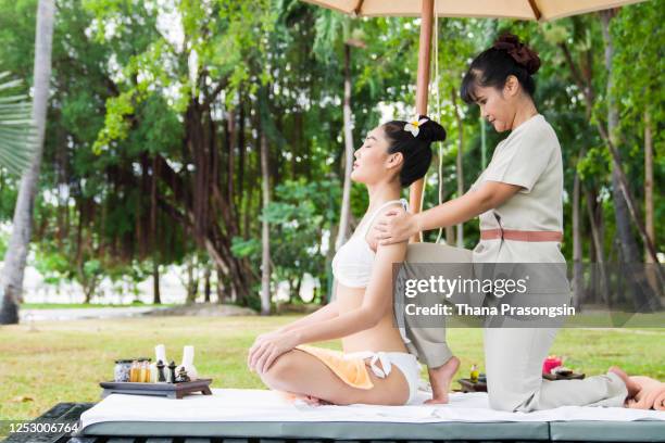 young woman receiving a massage on the balcony of her suite in a luxury vacation retreat - thai ethnicity fotografías e imágenes de stock