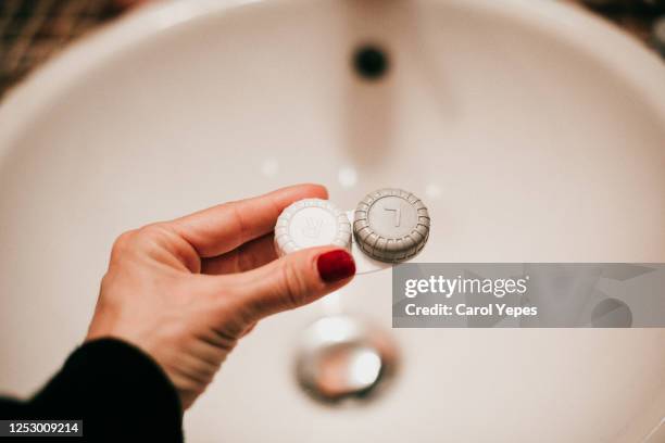 female hand holding contact lenses box in bathroom - liquid solution stock pictures, royalty-free photos & images