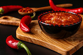 Traditional Maghrebi hot chili pepper sauce paste harissa on dark background, Tunisia and Arabic cuisine , horizontal orientation