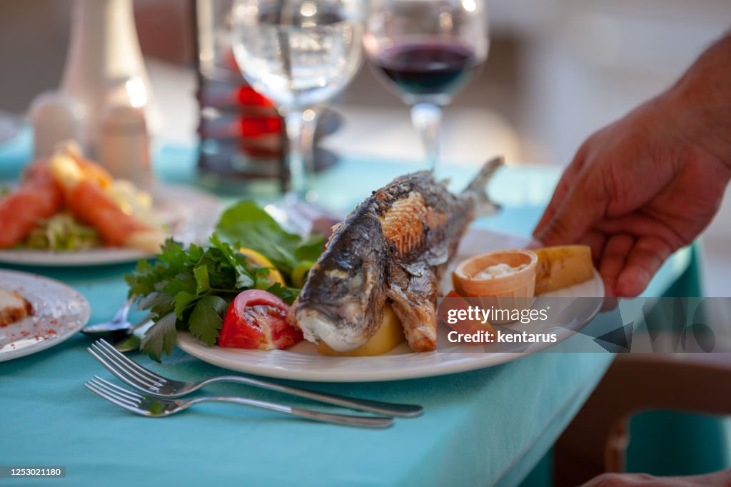 Roasted sea bream fish with special sauce, fresh vegetables and green salads