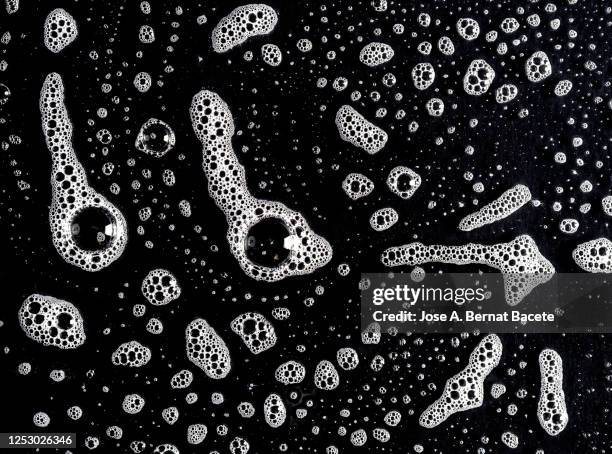 full frame of the textures formed by the soap bubbles on a black background. - froth stock pictures, royalty-free photos & images